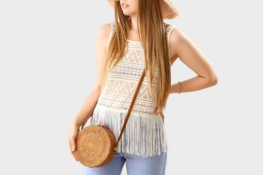 Young woman with stylish rattan bag on light background