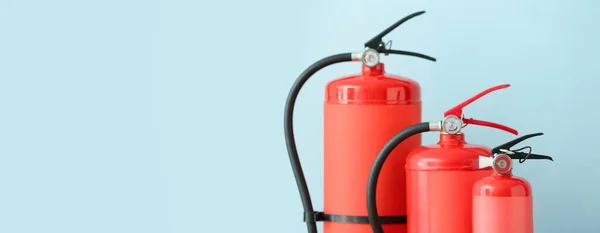 Fire extinguishers on light blue background with space for text