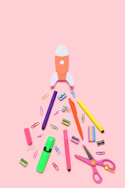 Paper rocket with school stationery on pink background