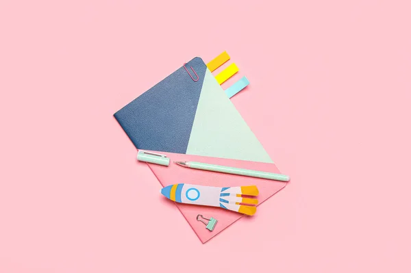 Paper rocket with school stationery on pink background