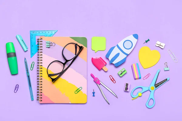 Paper rocket with school stationery and eyeglasses on violet background