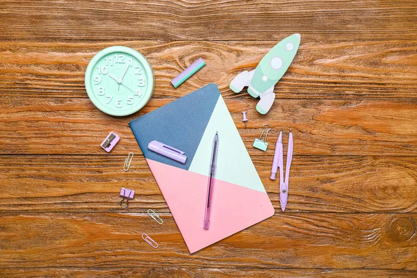 Paper rocket with school stationery and alarm clock on wooden background