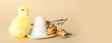 Cute toy chicken, pussy willow branches and Easter eggs on beige background