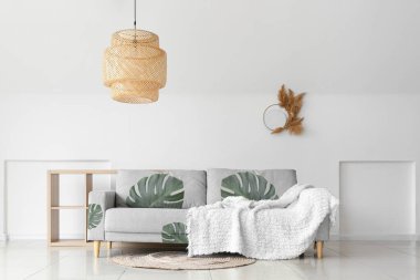 Oturma odasında canavar yaprakları olan rahat bir kanepe.