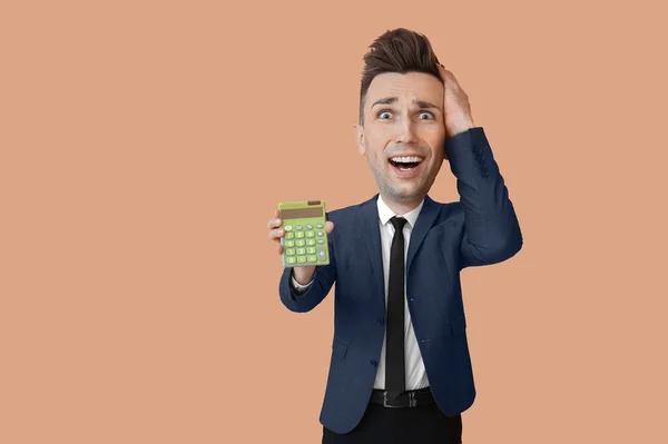 Funny stressed businessman with big head and calculator on beige background