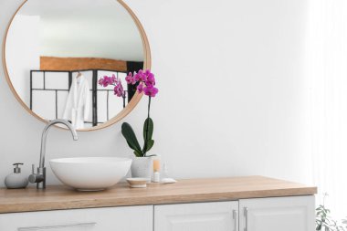 Modern sink and orchid flower on counter near white wall in bathroom