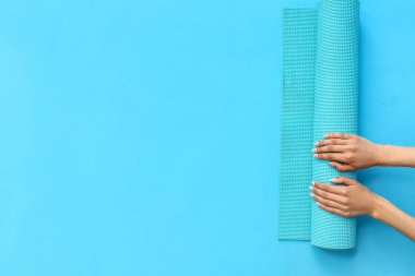 Renkli arka planda yoga minderi olan kadın eller
