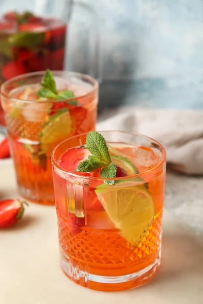 Glass of strawberry lemonade with mint leaves on white table, closeup