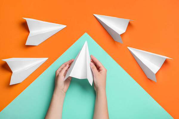 Woman with paper planes on color background