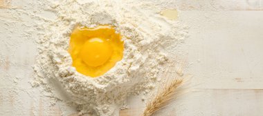 Beyaz ahşap arka planda buğday unlu çiğ yumurta.