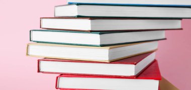 Pembe arkaplan üzerine kitap yığını, yakın plan
