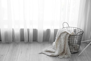 Ekoseli sepet, ışık perdesinin yanında.