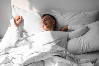 Evde yatakta uyuyan yakışıklı genç adam.