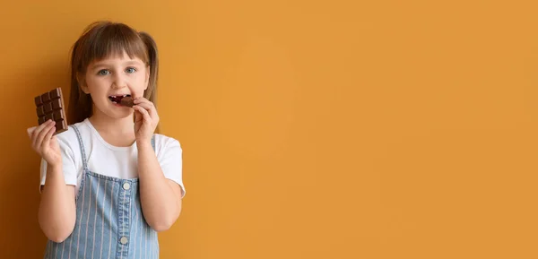 Cute Little Girl Eating Sweet Chocolate Orange Background Space Text — Stock Photo, Image