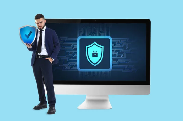 Businessman with icon of antivirus and big computer monitor on light blue background
