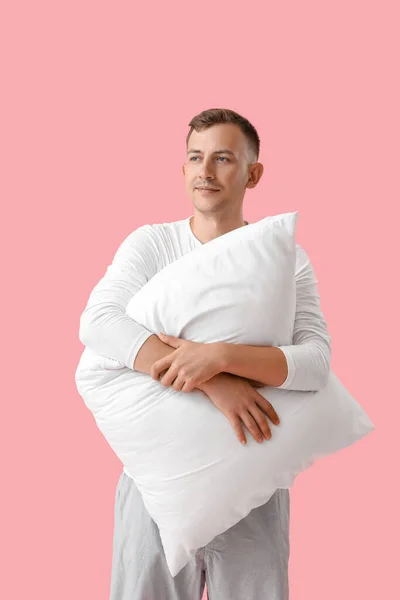 Young man with pillow on pink background