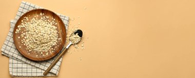 Plate of raw oatmeal on beige background with space for text