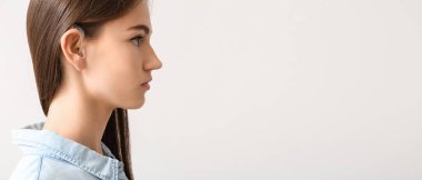 Young woman with hearing aid on light background. Banner for design 