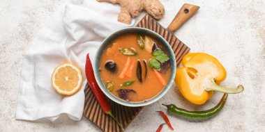 Arka planda bir kase baharatlı Tayland çorbası.