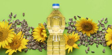 Bottle of sunflower oil and seeds on green background with space for text