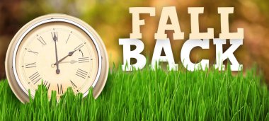 Clock on grass outdoors. Fall back concept