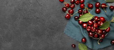 Bowl of tasty cherries on grey background with space for text, top view