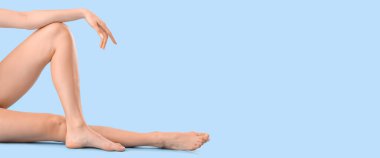 Legs of beautiful young woman on light blue background with space for text