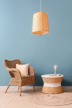 Rattan armchair and table near blue wall