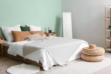 Interior of cozy bedroom with rattan poufs and mirror