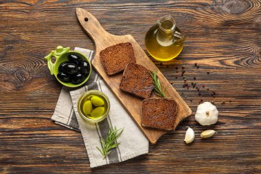 Composition with bowls of olives, bread and fresh oil on wooden background