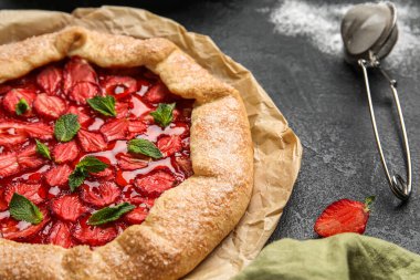 Tasty strawberry galette on dark background, closeup