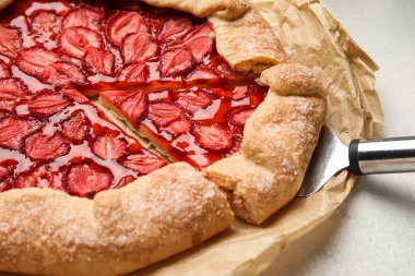 Tasty strawberry galette with spatula on table, closeup