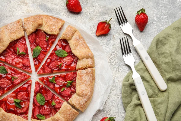Fresh strawberry galette, fresh berries and forks on light background
