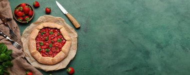 Composition with delicious strawberry galette on green background with space for text