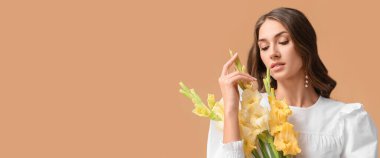 Elegant young woman with holding bouquet of gladiolus flowers on beige background with space for text