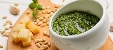 Bowl of tasty pesto sauce on table closeup