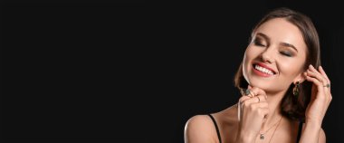 Portrait of pretty woman wearing stylish jewelry on black background with space for text
