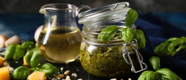 Taze pesto soslu kavanoz ve masada malzemeler.