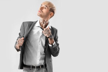 Young tattooed man with necktie on light background