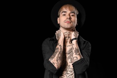 Young tattooed man on black background