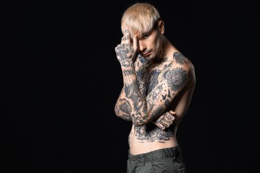 Young tattooed man on dark background