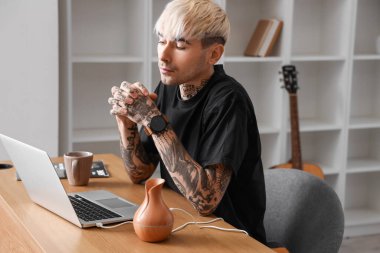 Young tattooed man using laptop at home