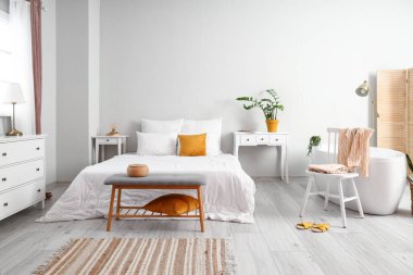 Interior of light bedroom with bathtub
