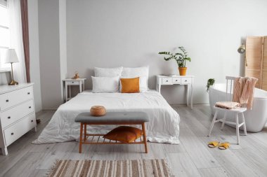 Interior of light bedroom with bathtub