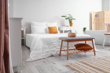 Interior of light bedroom with bathtub