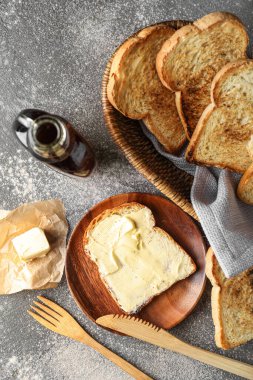Composition with tasty toasts and bottle of maple syrup on grunge background