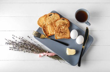 Composition with tasty breakfast and lavender flowers on light wooden background