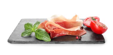 Slate board with delicious jamon, tomatoes and basil on white background
