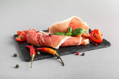Board with delicious jamon and spices on light background