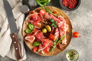 Wooden plate with delicious jamon on grunge background